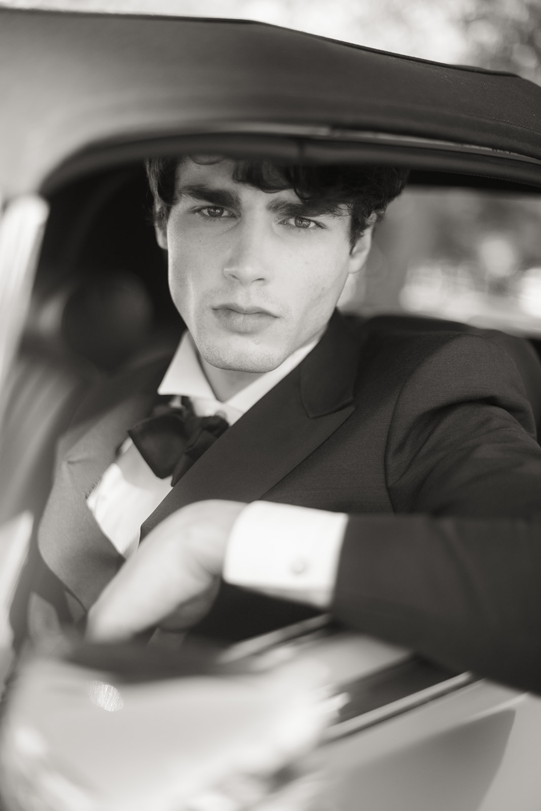 Close editorial portrait of a groom inside a vintage Jaguar